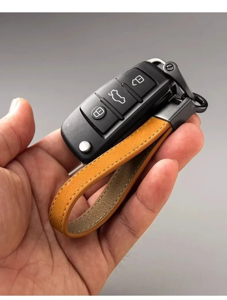 Black Audi key fob attached to a tan suede leather car keychain ring with a leather strap.