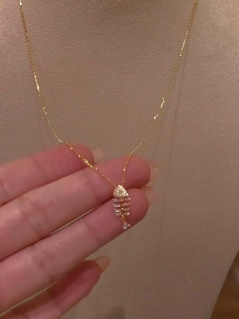 A delicate gold chain necklace featuring a small fishbone pendant adorned with clear crystals showcasing crystal fishbone gold necklace pendant jewelry.