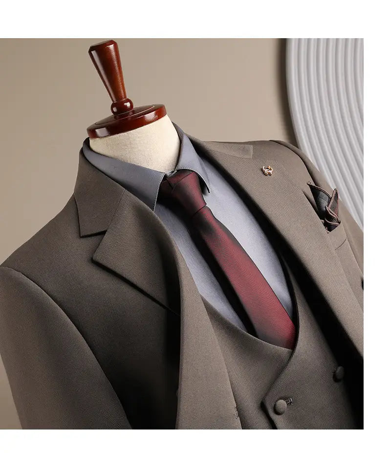 Ensemble costume d’affaires pour homme gris anthracite slim fit trois pièces, élégant, comprenant un gilet assorti, une chemise bleu clair nette et une cravate bordeaux riche, adapté aux occasions d’affaires en mode masculine et de soirées décontractées.