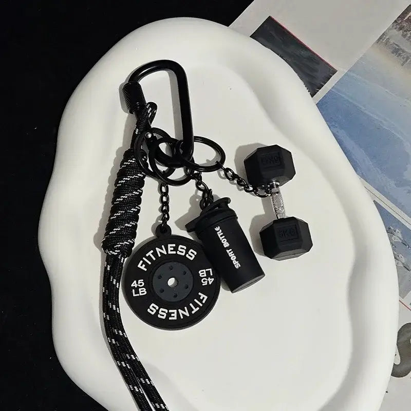 Black fitness keychain featuring a 45 lb weight plate dumbbell and sport bottle charm as a colorful gym bag accessory.