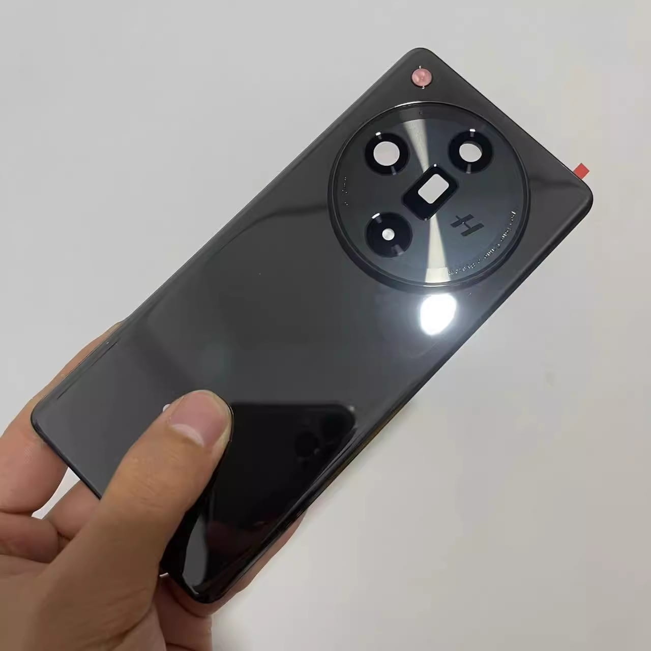 OPPO Find X7用の黒の光沢バックカバーで、円形のトリプルレンズカメラモジュールとピンクのアクセントを備え、カバーの修理、交換、ならびにドアフォン用途の修理・交換に使用するための設計です。