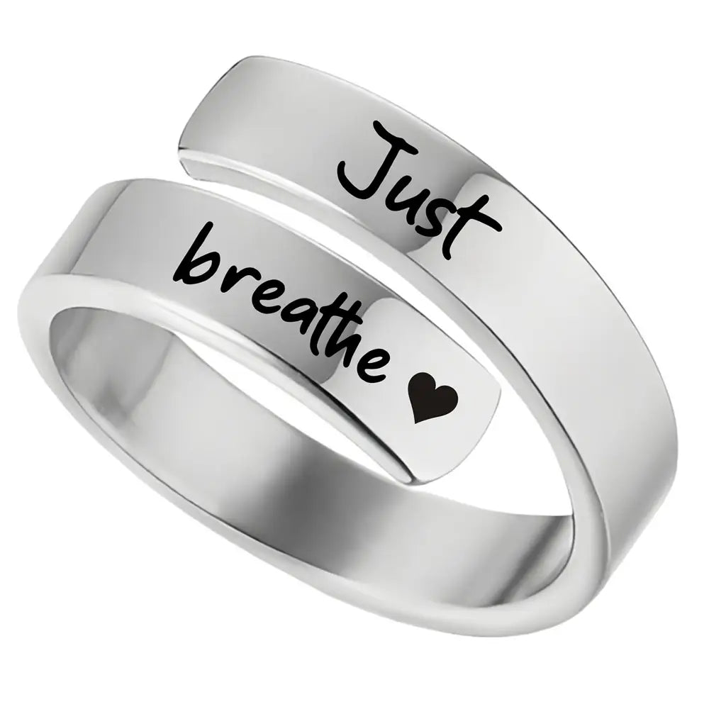 Stainless steel silver wrap-around just breathe anxiety ring with black script engraving and a small heart symbol.