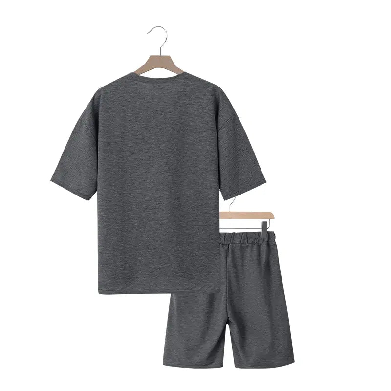 Conjunto veraniego de dos piezas para hombre, que presenta una camiseta de algodón gris jaspeado y conjunto de pantalones cortos a juego, exhibidos en perchas de madera.