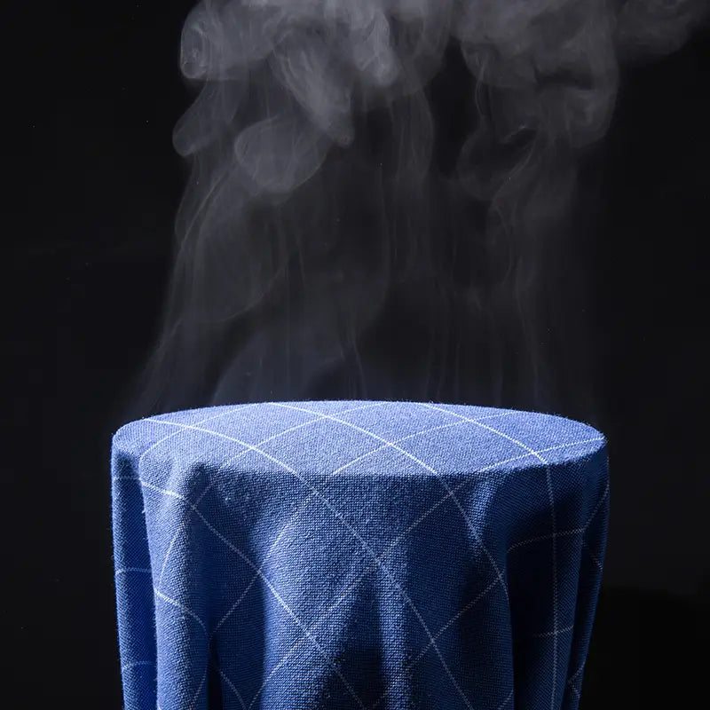 Chemise habillée Oxford en coton 100 % à carreaux bleu marine, coupe slim, drapée sur un objet cylindrique, avec de la fumée s’élevant depuis le haut.