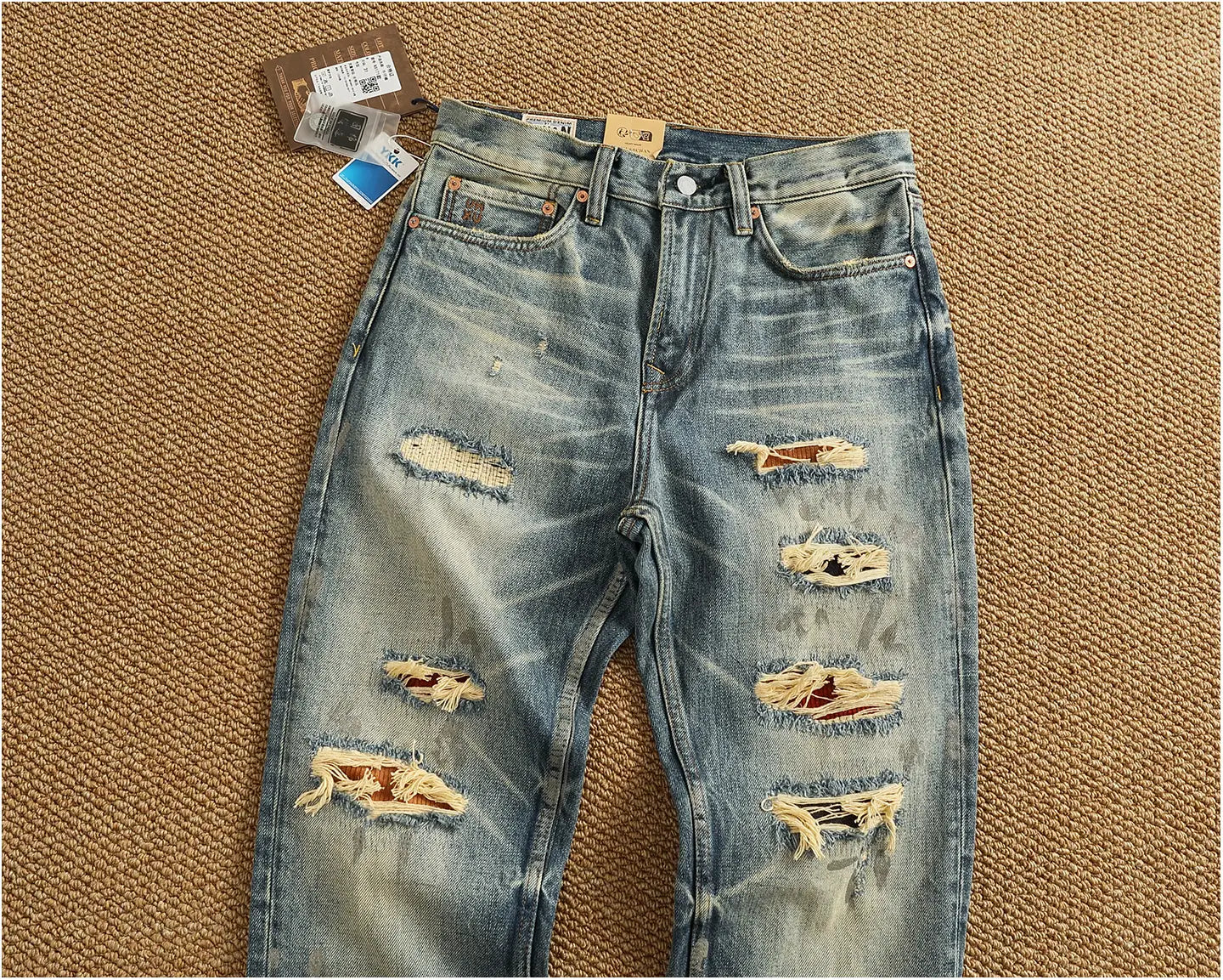 distressed patchwork denim jeans men featuring blue denim with multiple frayed tear holes and a faded worn-in look