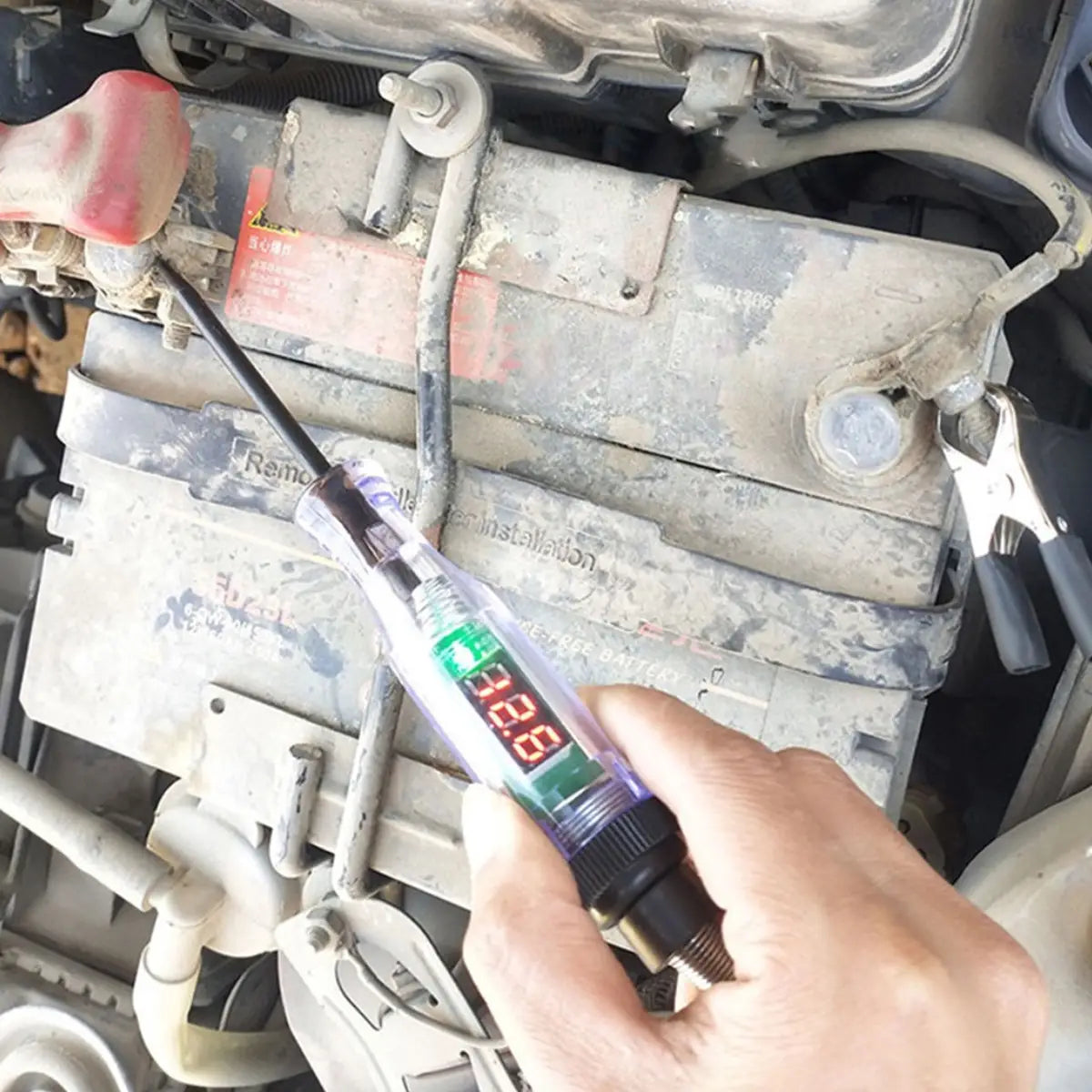 An automotive digital voltage circuit tester pen in translucent purple and black with a green led display showing 3.28 is being used to test electrical components under the hood of an older vehicle.