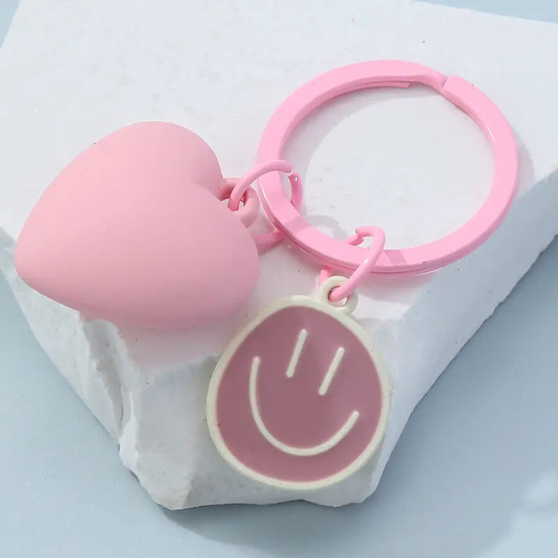 Pink silicone keychain with a heart-shaped charm and a smiley face pendant designed for easy attachment and daily use.