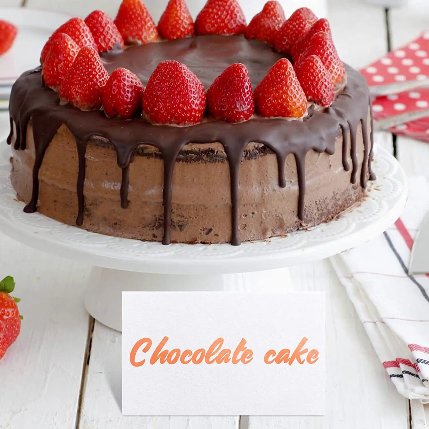 濃厚なチョコレートのフロストケーキ。新鮮な赤いイチゴをのせ、艶のある濃いチョコレートをたらした様子を、ユーカリの葉のプレースカードとともに示しています。ウェディングテーブル着席用です。