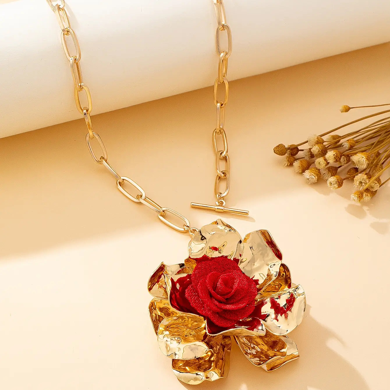 Gold chain necklace featuring a prominent red rose pendant with textured petals and reflective gold leaf accents from the red floral jewelry set gold rose necklace and earrings.