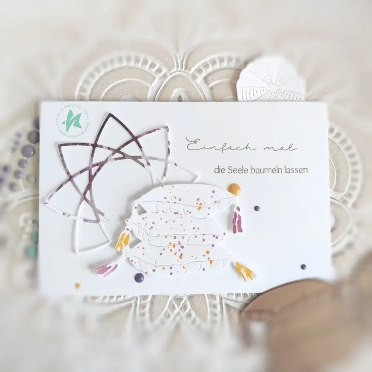 Eine weiße Papierkarte mit einem mehrschichtigen Stanzdesign einer verspielten Fische mit bunten Sprenkeln und metallischen Akzenten aus den Oster-Ei-Hasen-Babyschneidvorlagen.