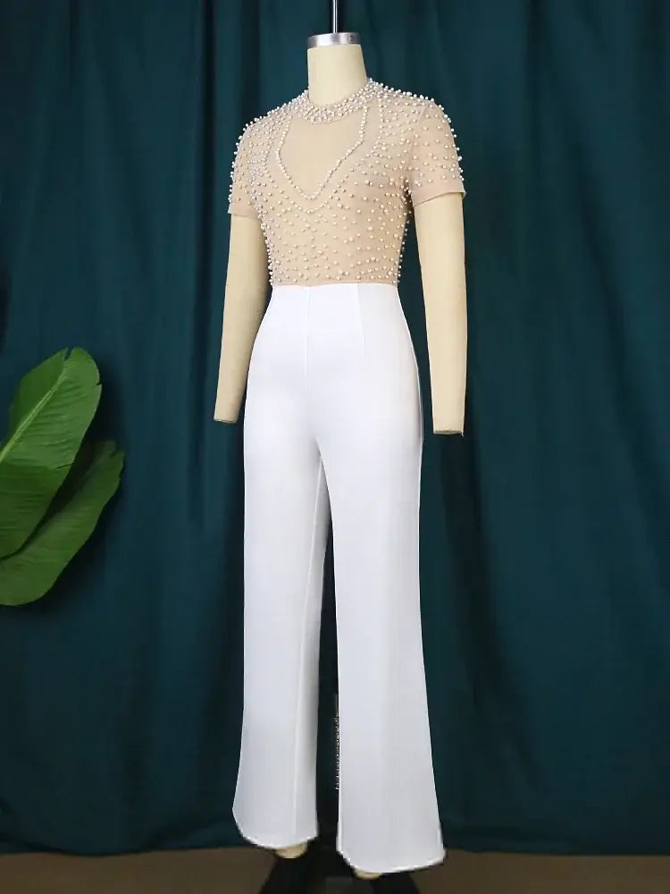 Beige beaded short-sleeve top paired with white high-waisted wide-leg pants in an elegant party outfit.