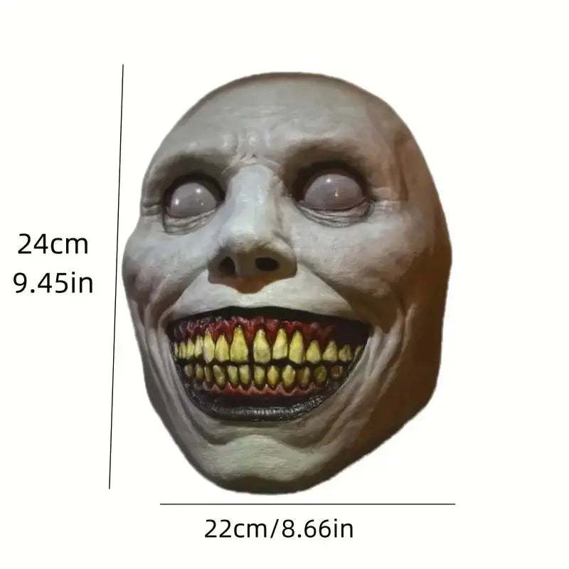 A pale latex full face horror mask with exaggeratedly wide eyes and a grotesquely smiling mouth lined with yellowed teeth designed as a creepy Halloween resin costume accessory.