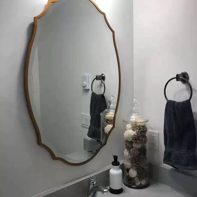 Miroir de salle de bains ovale doré, cadre à volutes ornemental, mettant en valeur un style de miroir élégant pour une décoration murale