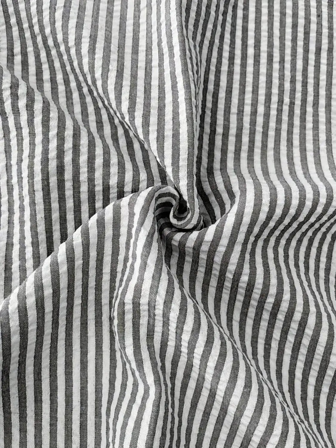 chemise décontractée boutonnée manches longues à rayures bleues pour homme fabriquée dans un coton à rayures verticales noir et blanc, avec une texture froissée discrète