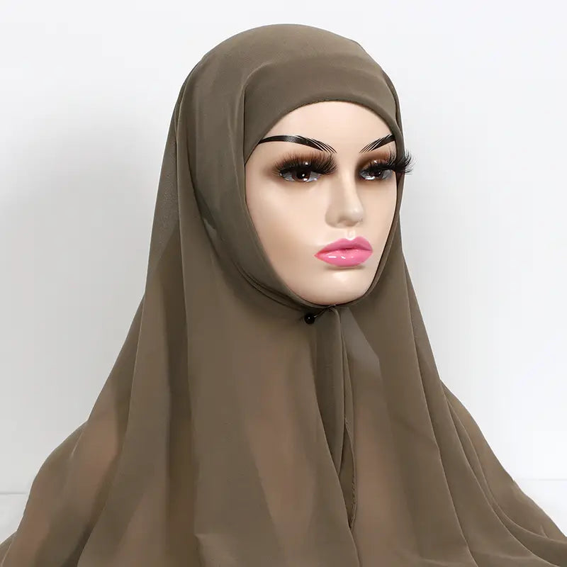 a soft taupe-colored instant chiffon hijab with cap bonnet made of lightweight fabric drapes elegantly over a mannequin head