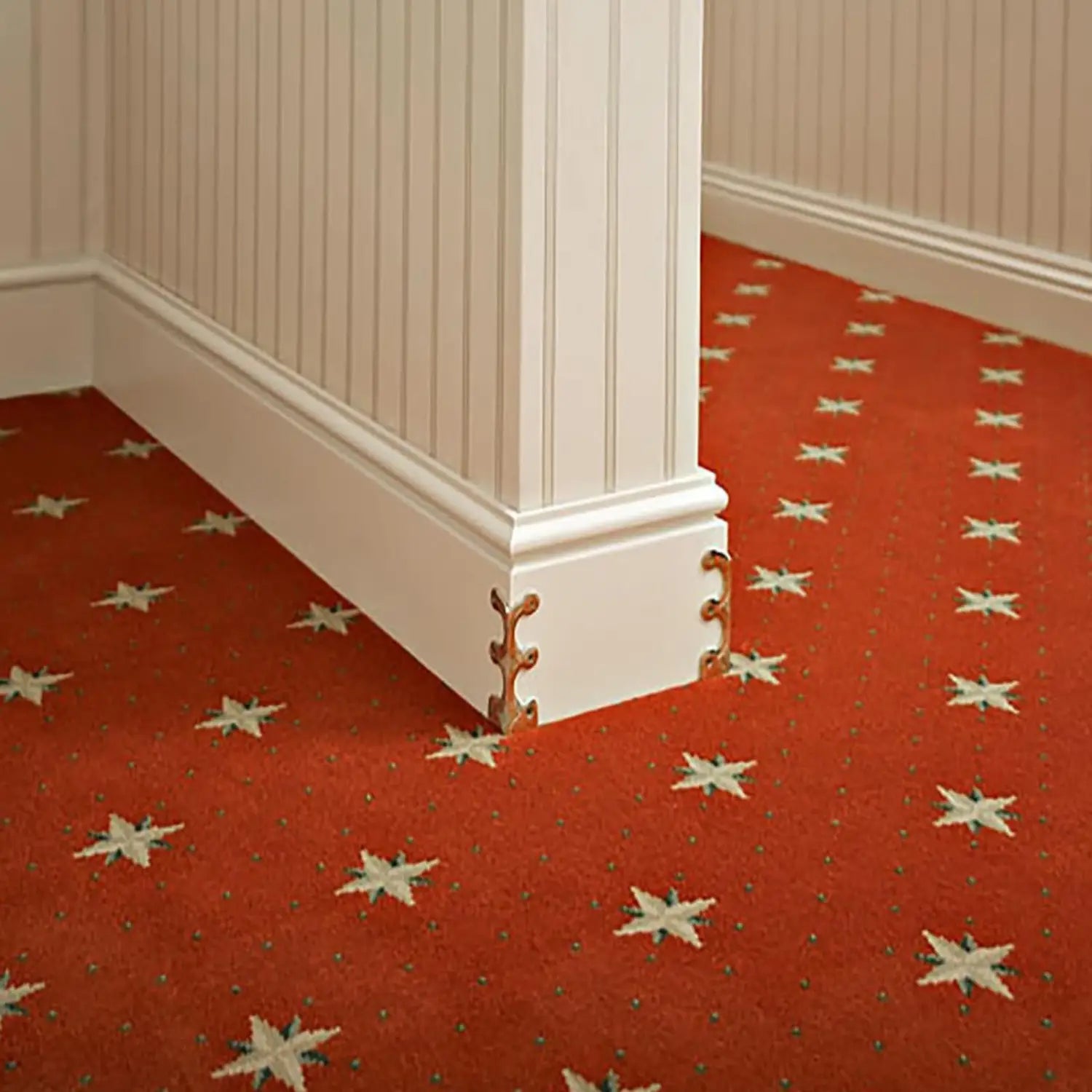 White metal skirting board edge guard with gold leaf decorative accents at the corner for protective and aesthetic purposes.
