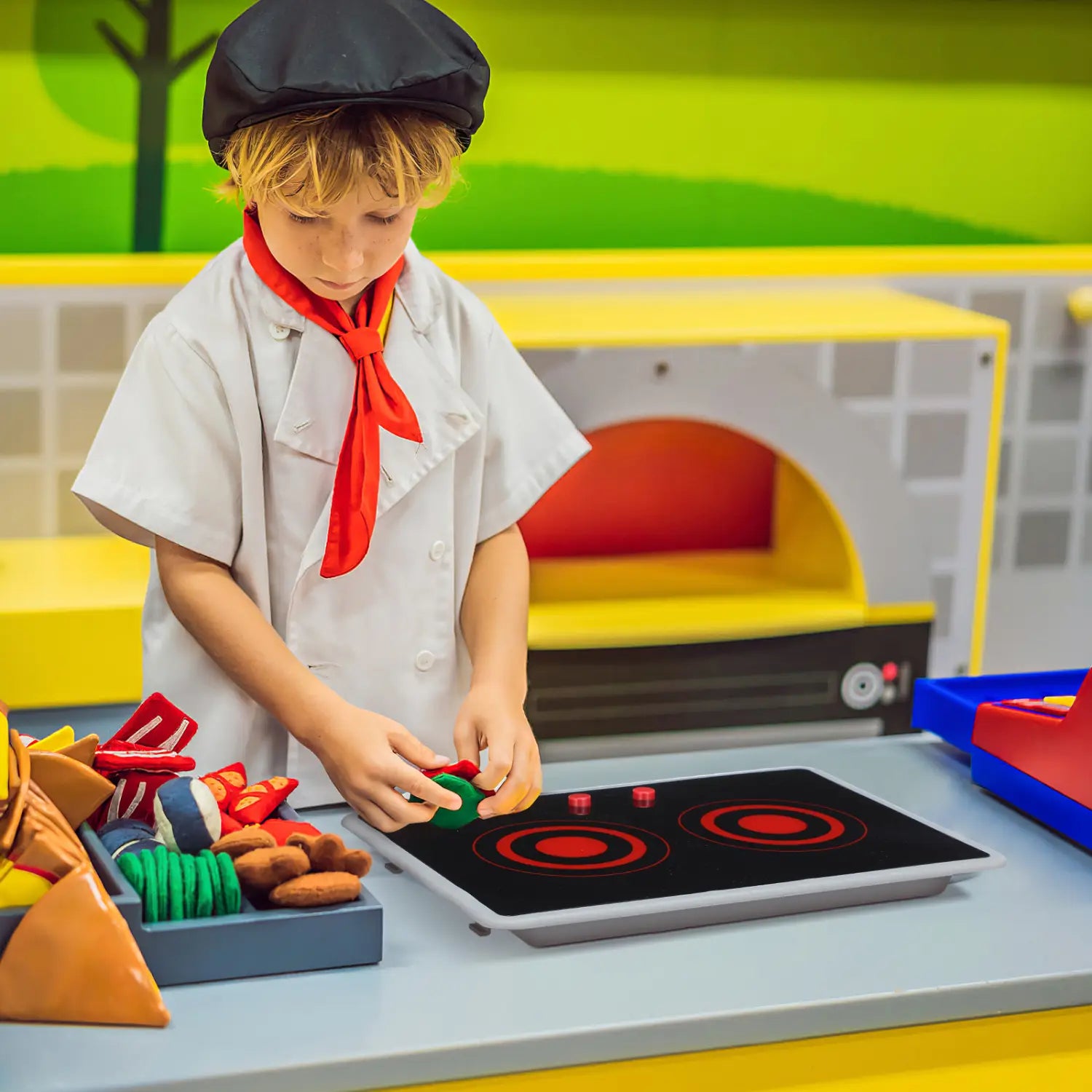 Schwarze und rote Kinder spielen mit einem Induktionsherd-Spielzeug mit Sound- und Lichtfunktionen und zwei runden Heizelementen.