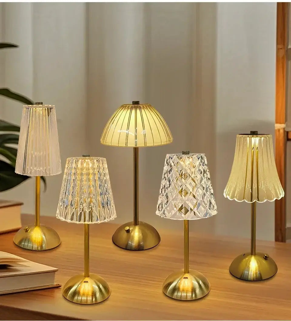 Fünf elegante, goldfarbene Messing-Tischlampen mit Kristallgläsern in kunstvollen plissierten und facettierten Mustern als dekorative Lichtquelle.