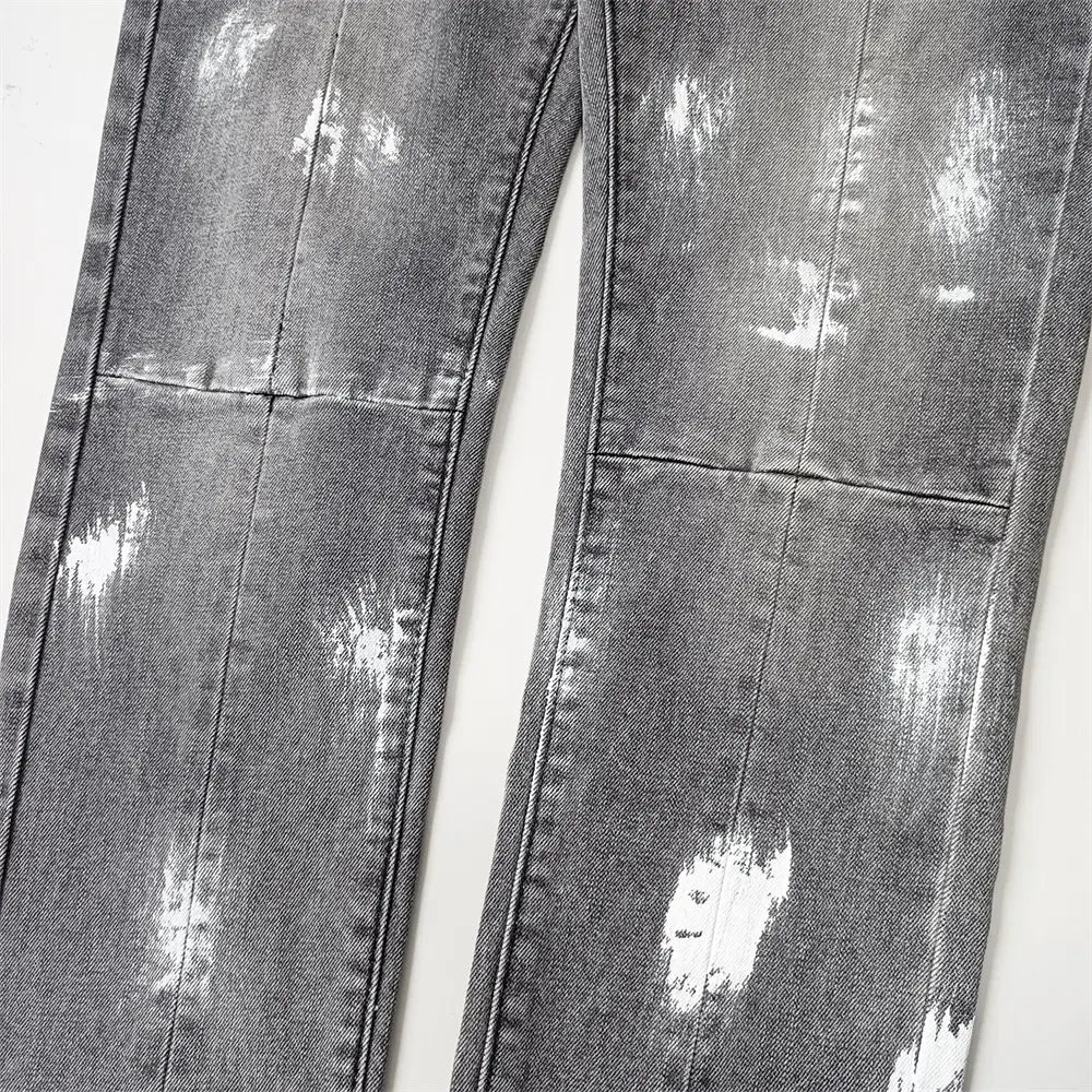 Jeans skinny déchirés pour hommes en denim gris délavé, avec effets d’éclaboussures de peinture blanche et détails en bleu de délavage rétro vintage.