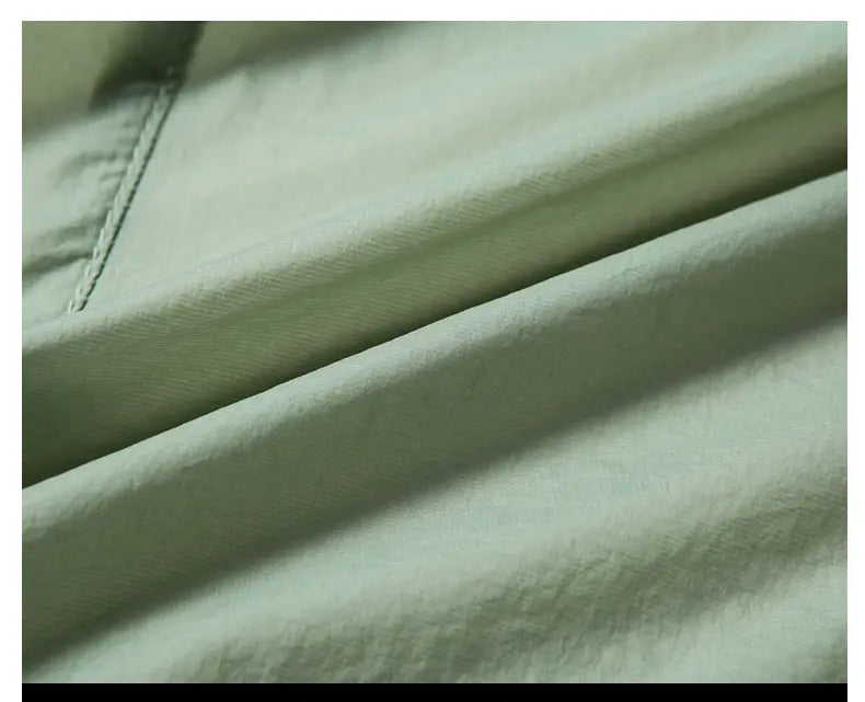 Heller grüner Polyester-Baumwollstoff mit dezentem Strukturrelief und sichtbarer Steppnaht entlang der Naht an einer Herren-Freizeit-Blazer-Anzugjacke