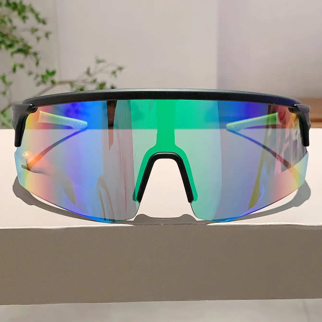 Lunettes de soleil de sport surdimensionnées à monture noire, verres irisés teintés arc-en-ciel passant du bleu au vert, conçues pour un usage de cyclisme.