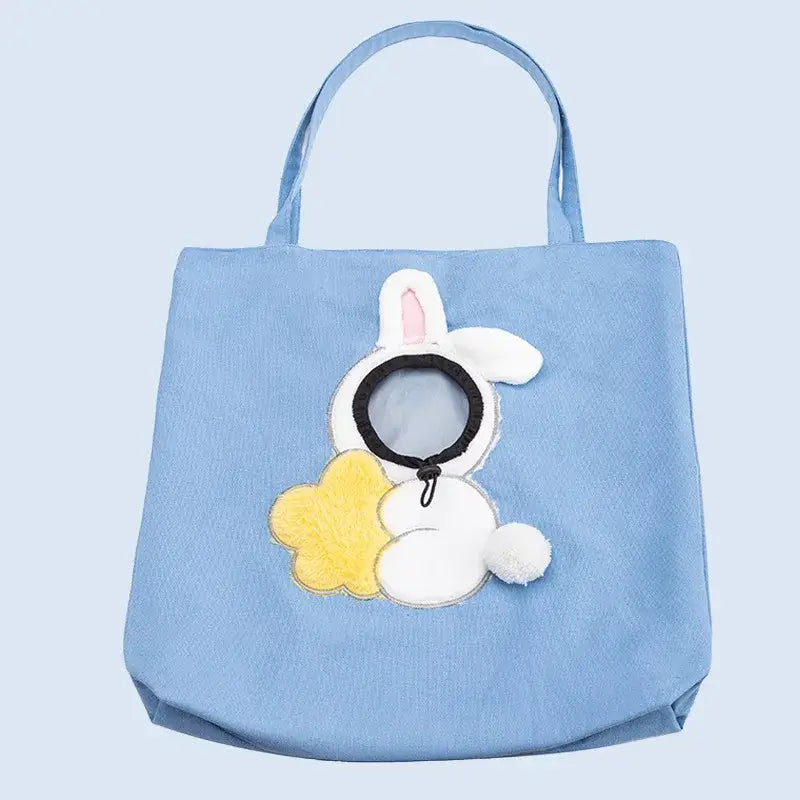 light blue canvas pet carrier bag featuring a white bunny appliqué with pink inner ears holding a yellow cloud-shaped pouch and a black circular accessory suitable for small dog and cat use with an emphasis on mouth length.