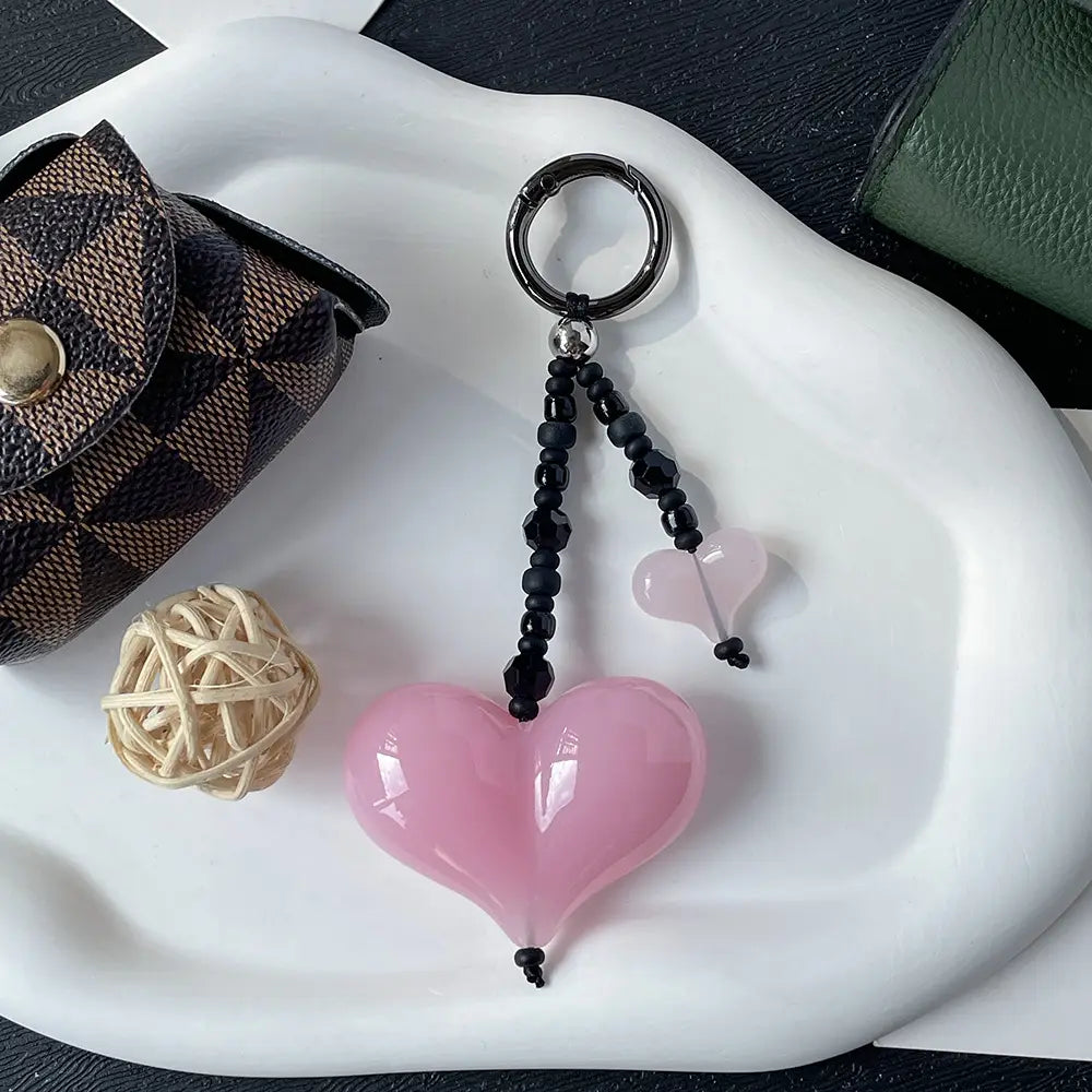 Porte-clés en forme de cœur rose brillant avec des perles noires et un anneau en argent, utilisé comme pendentif pour sac à perles.