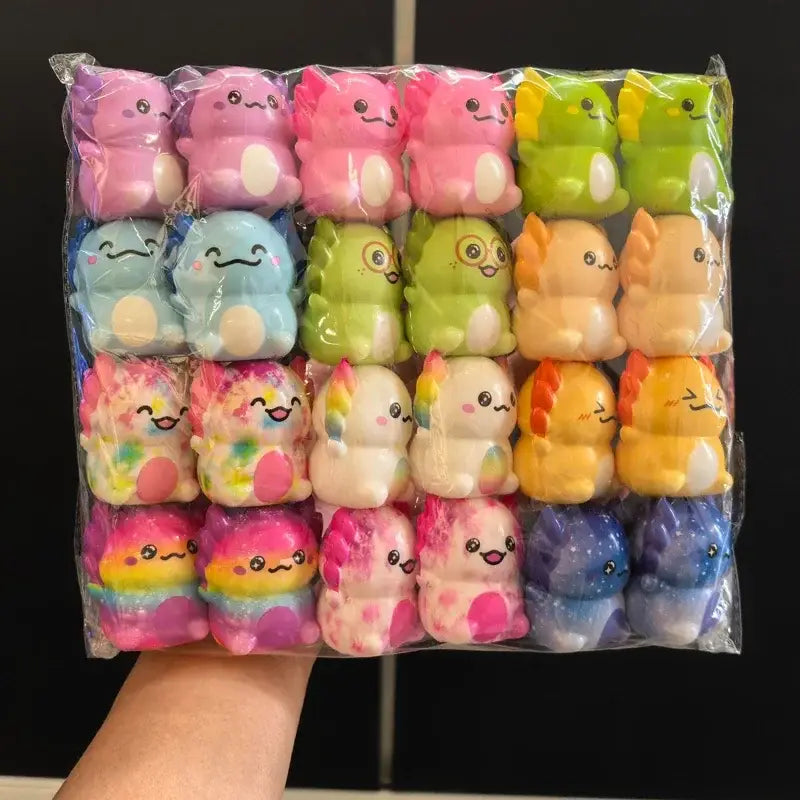 Eine bunte Zusammenstellung von Knet- und Quetschplüschspielzeugen in Dinosaurier- und Einhornform in einer klaren Kunststoffverpackung aus dem Axolotl-Knet- und Quetschspielzeug-Set, entwickelt für Stressreduktion und spielerische Sinneserfahrungen