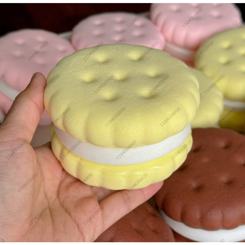 Ein weichgelbes Silikon-Großkeks-Knautschspielzeug mit langsam ansteigendem Effekt, mit einer strukturierten, keksartigen Oberseite und weißer Füllung, die einem realistischen Kuchen ähnelt.