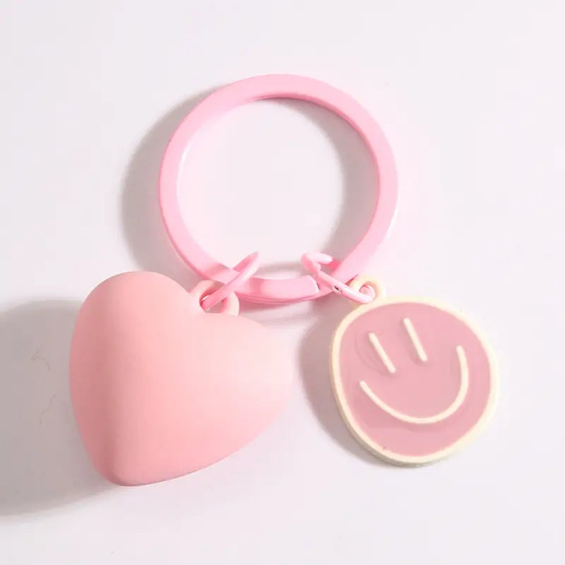 Pink silicone keychain featuring heart and smiley face charms for decorative use.