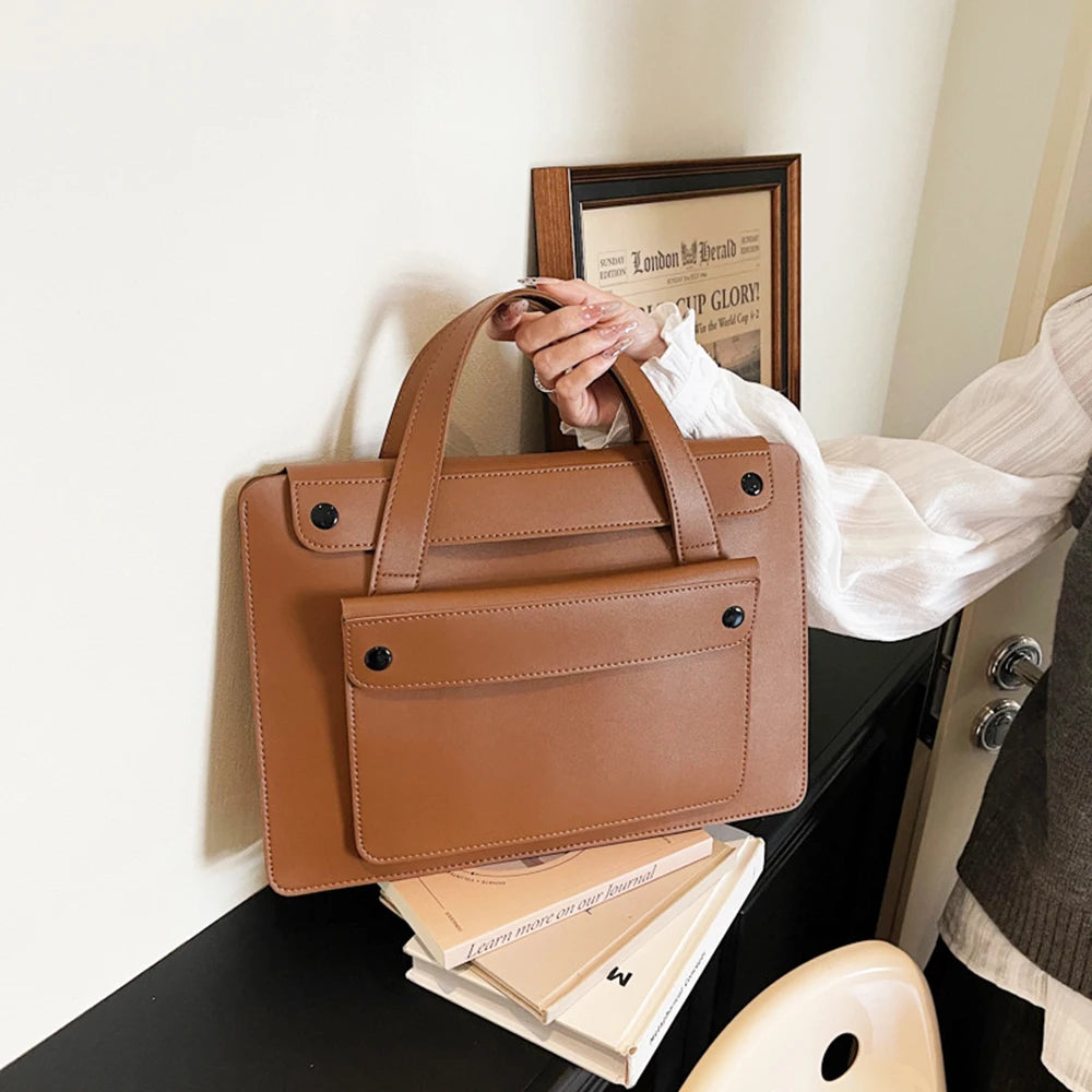 Tan leather laptop briefcase for women with structured design and black rivet accents.