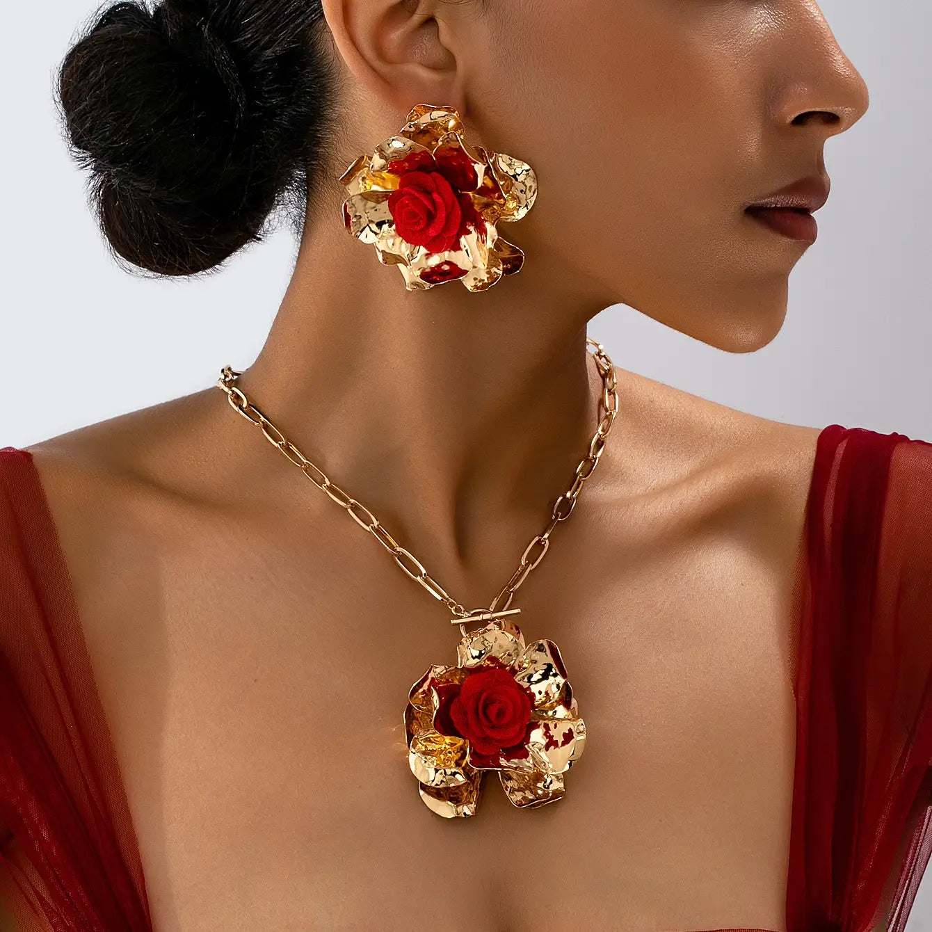 Red floral jewelry set gold rose necklace and earrings featuring a gold-toned rose-themed necklace with a bold layered design and a vibrant red central flower accent.