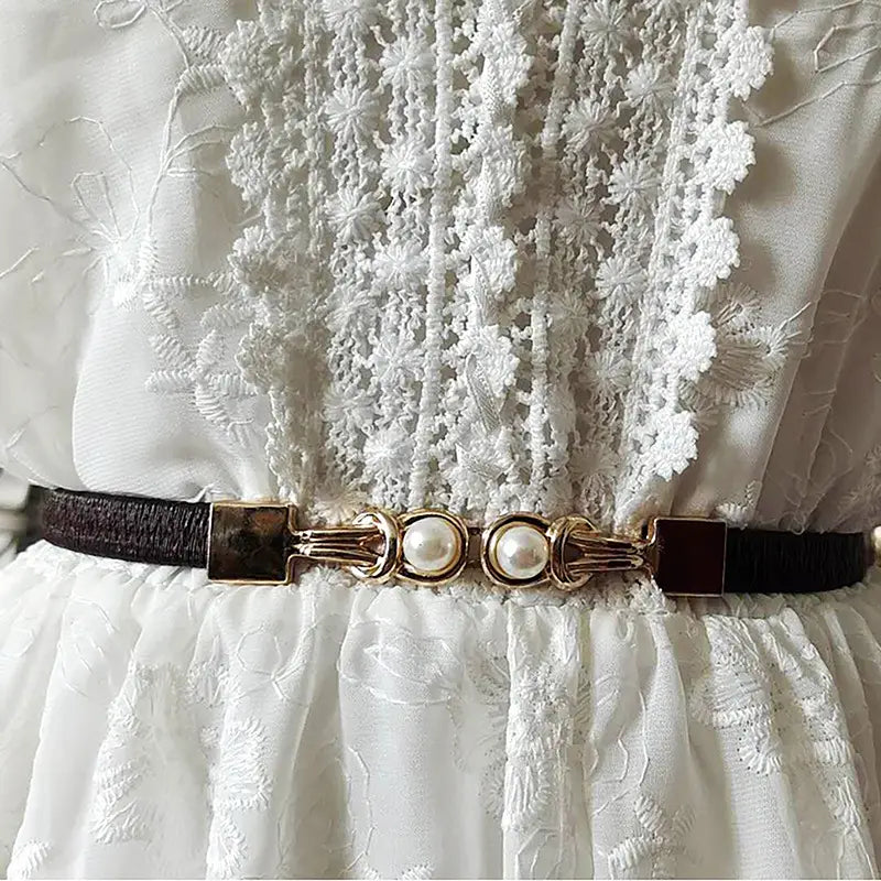 Ein zarter schwarzer Lederperlen-Schnallen-Taillegürtel für Damen mit einer goldfarbenen Schnalle, verziert mit zwei perlenähnlichen Zierelementen.