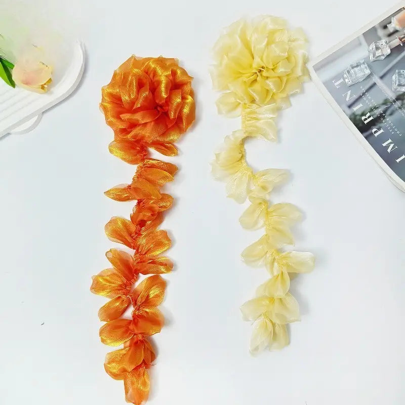 オーガンジーの花タッセル・ブローチピン用として、シアーで光沢のあるオーガンジー生地にフリルのペタルデザインを施した、鮮やかなオレンジとやわらかなクリームの2つの装飾リボンフラワーチェーン。