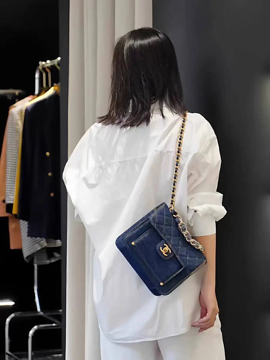 Navy blue quilted leather Chanel handbag with gold-tone hardware and chain strap complementing a solid white basic shirt oversized casual button up blouse.