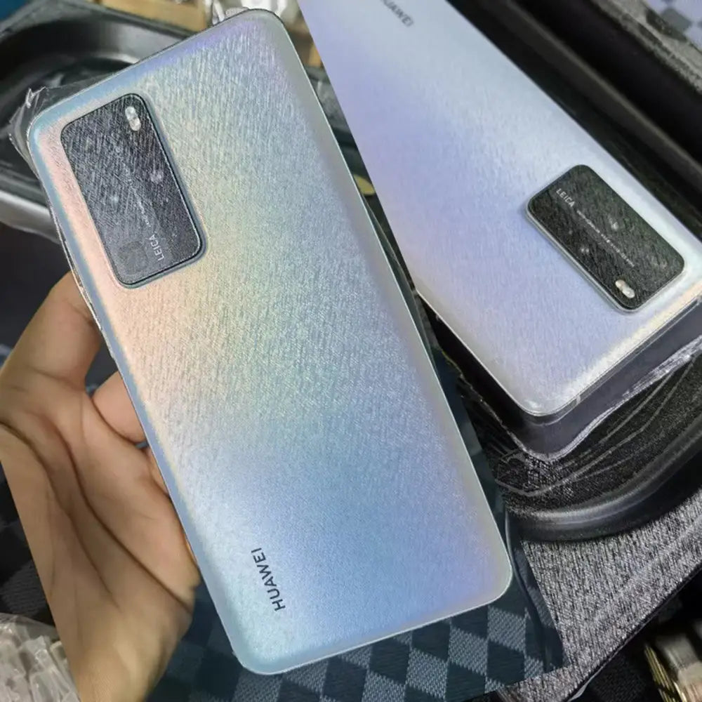 Un teléfono móvil Huawei con panel posterior nacarado texturizado que transita entre tonos azules suaves y plata, mostrado junto a una máquina de laminación al vacío de película para teléfonos móviles, destacando una gestión eficiente del costo de envío.