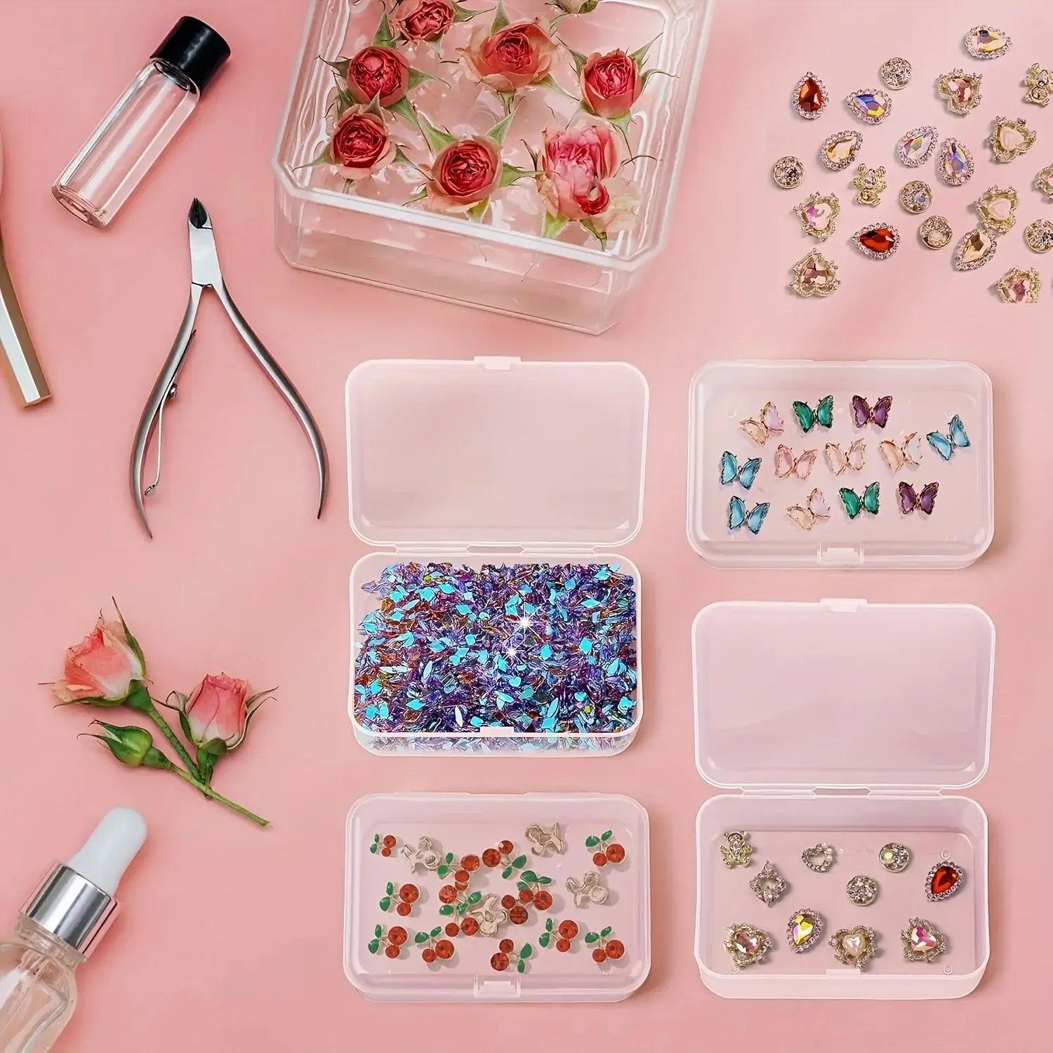 Boîtes de rangement en plastique transparent, remplies d’éclats de strass multicolores en forme d’ornements papillon et de motifs floraux, destinées aux travaux de nail art et de création de bijoux.