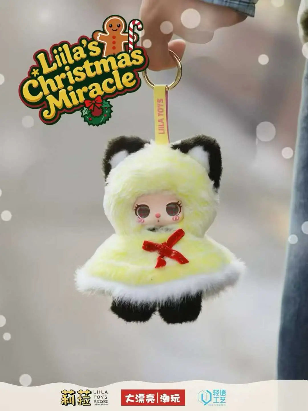クリスマスアドベンチャーのブラインドボックスペンダントコレクションに収められた、黒い耳と肉球を持つ淡いペールイエローのやわらかなぬいぐるみ風ビニールドールのパンダキーチェーン。ふわふわの冬用コートと赤いリボンを着用している。
