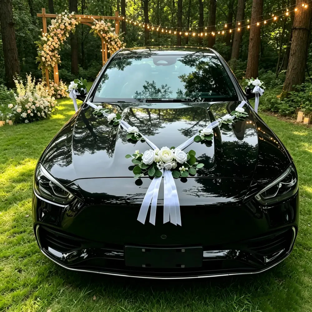 berline noire brillante décorée de roses artificielles blanches et d’arrangements floraux d’eucalyptus, ainsi que de rubans, en tant que décoration de kit de décoration de voiture de mariage