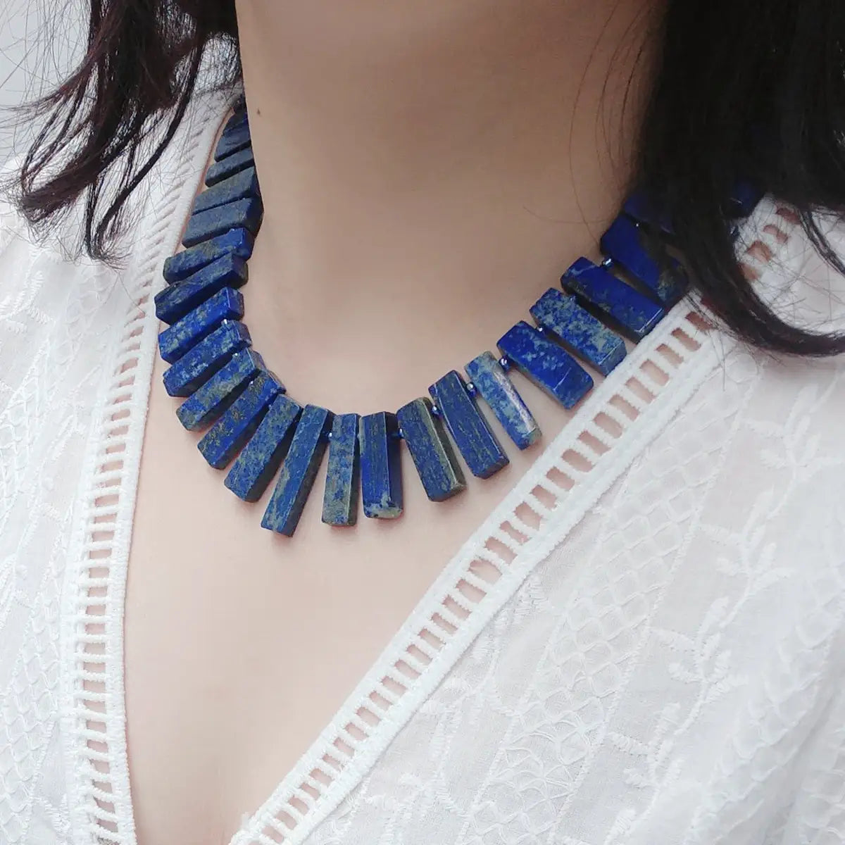 Un collier ras du cou audacieux en lapis-lazuli bleu profond, composé de perles de pierre rectangulaires conçues comme une pièce de bijouterie de déclaration.