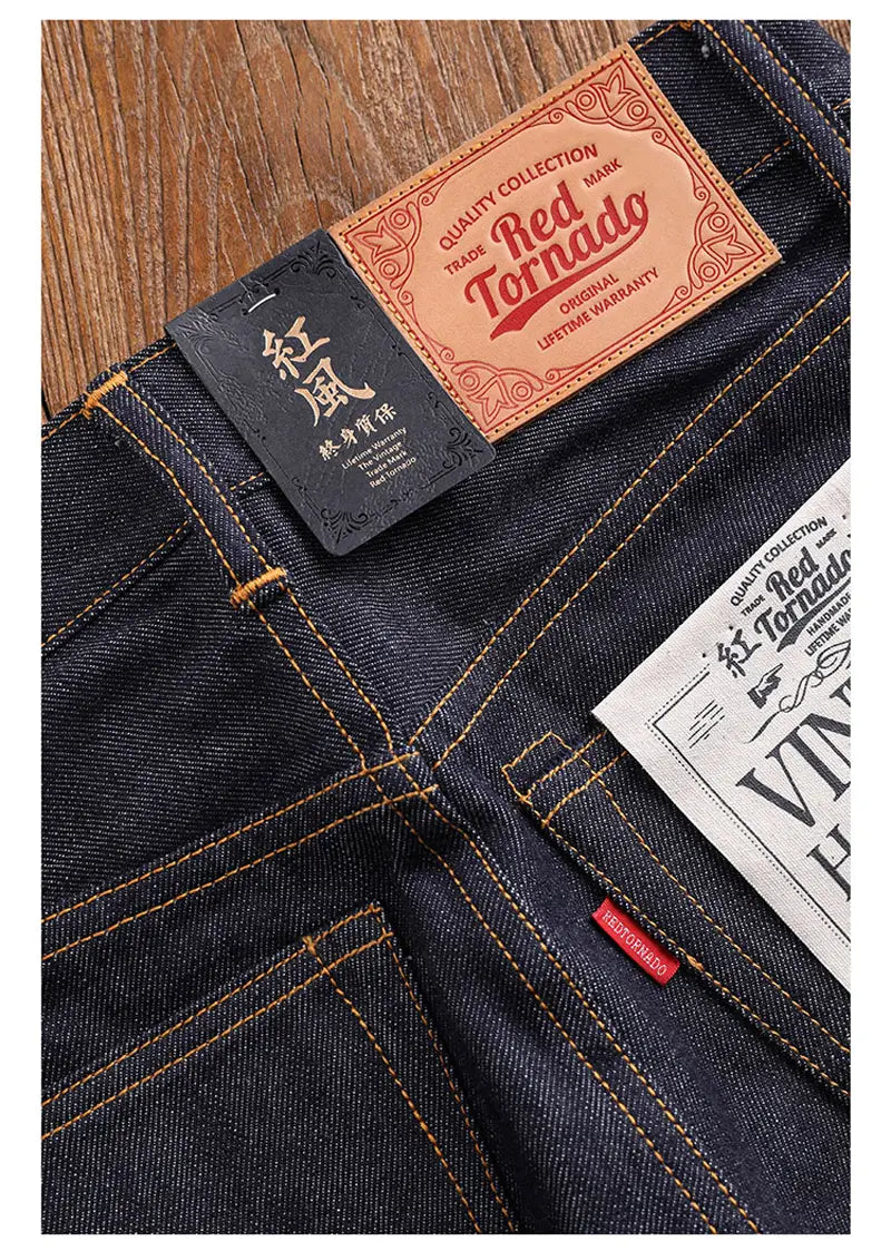 Jeans en denim indigo foncé « red tornado » en selvedge slim droit 16 oz, avec des surpiqûres orange et des empiècements en cuir portant la marque, présentés du côté arrière