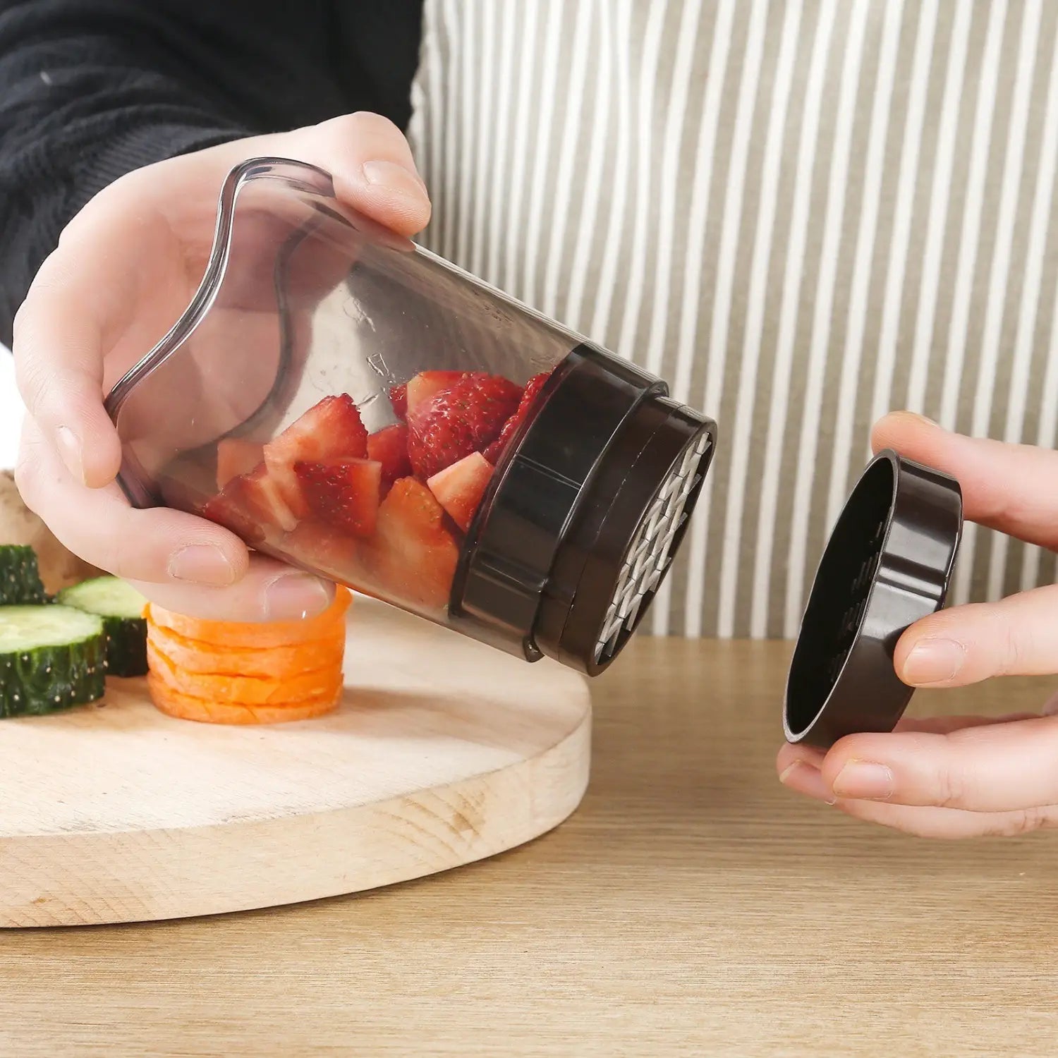 Transparent plastic handheld fruit and vegetable chopper slicer with black mesh and lid designed for easy strawberry and food prep.