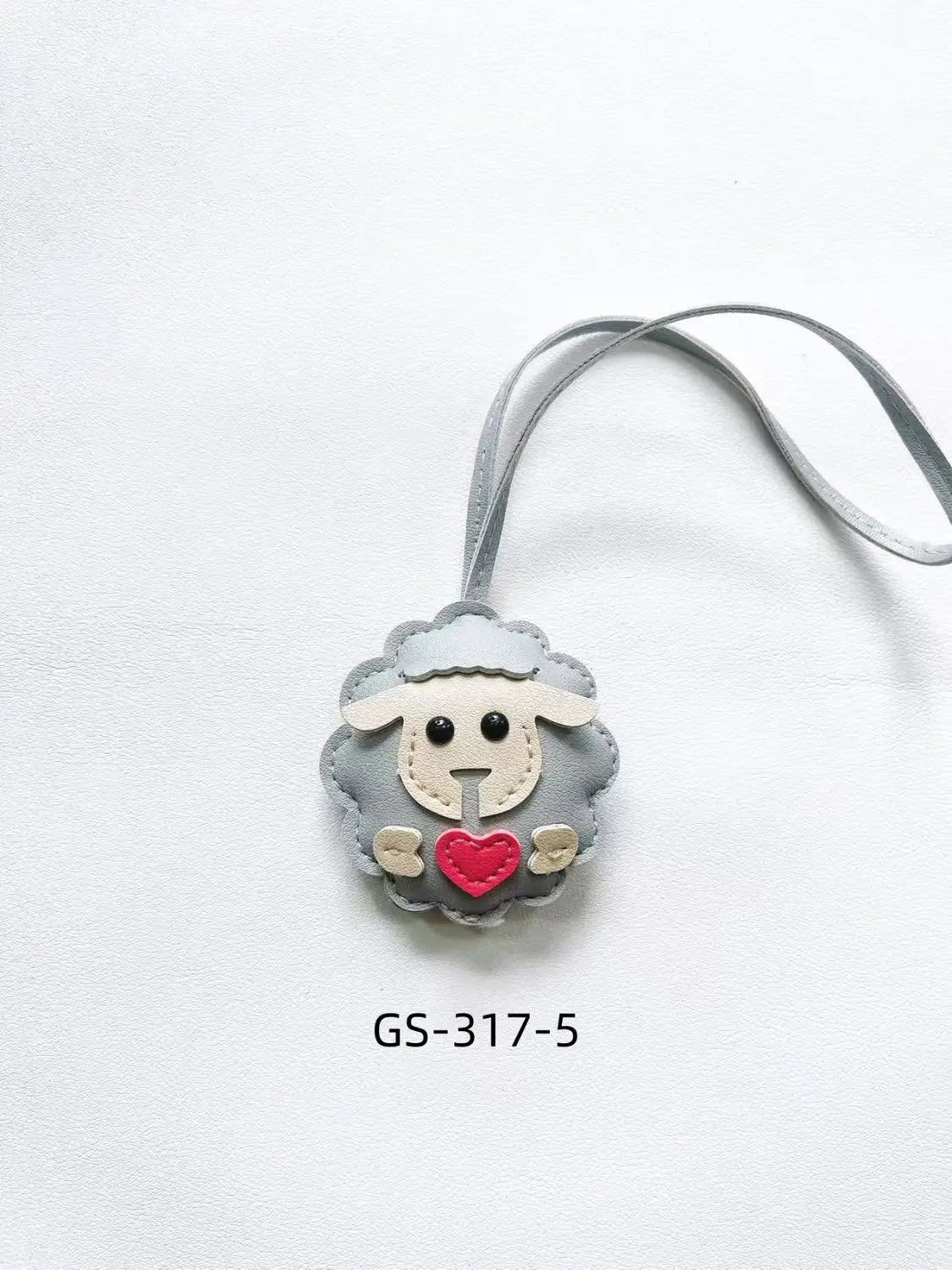 Gray felt leather sheep keychain with red heart detail and black button eyes attached to a matching gray strap for use as a cute animal bag charm.
