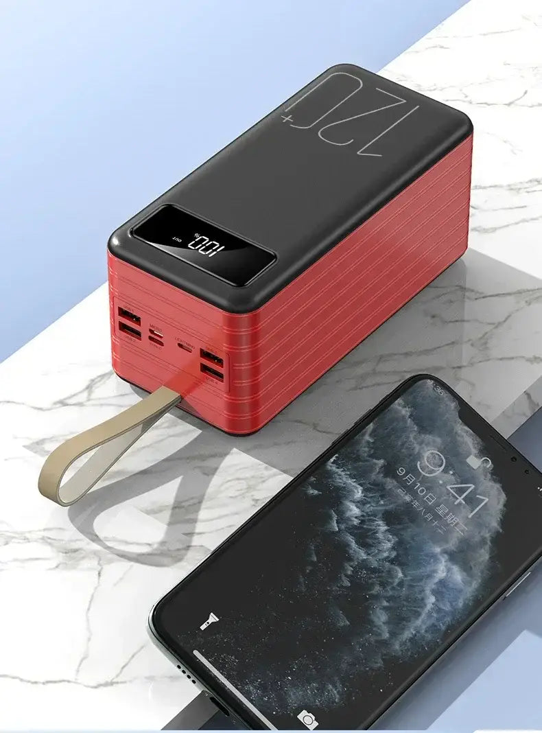 Red and black rectangular portable power bank with a textured surface, beige carrying strap, digital display showing 100 percent, multiple USB ports, and 120000mAh 66W fast charging capabilities.