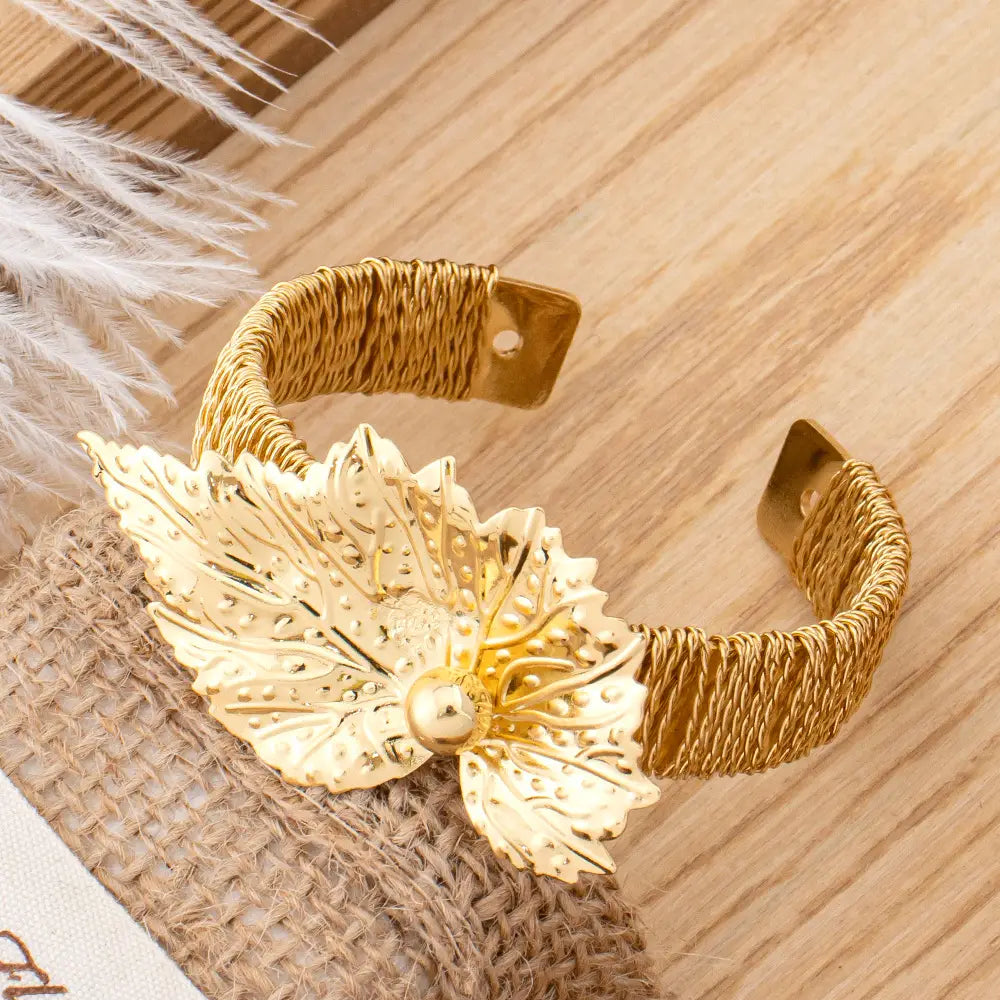 Bracelet manchette en forme de feuille d’or, avec des détails complexes et un accent de perle centrale, issu de la parure de bijoux en perles et feuilles d’or.