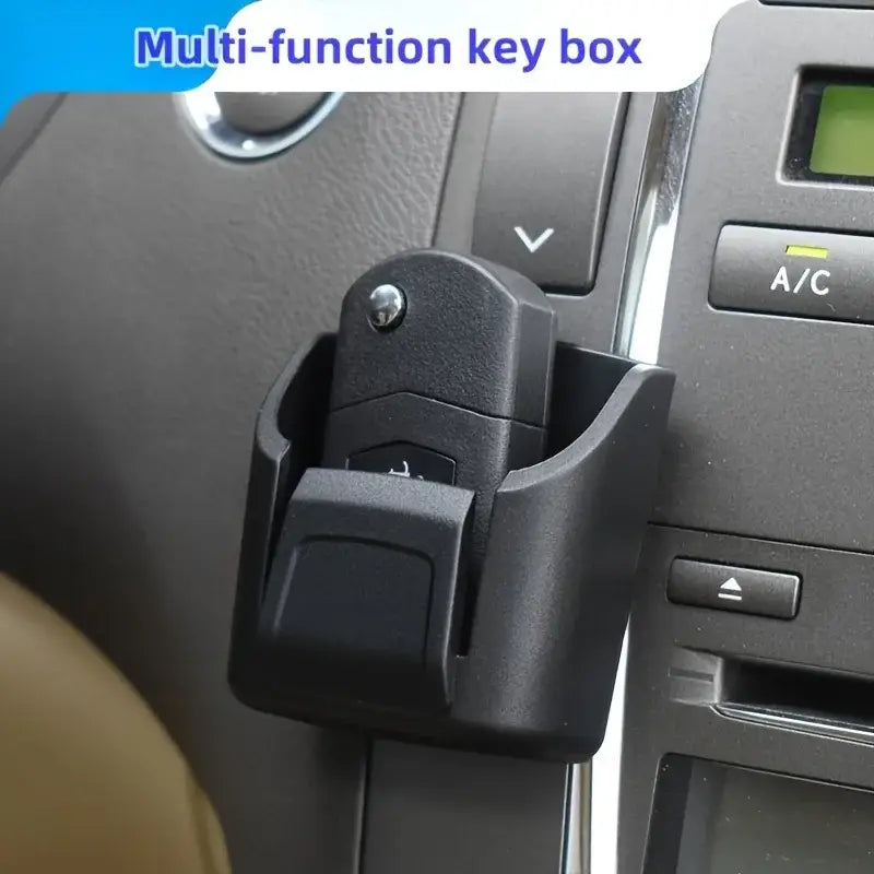 Black plastic multi-function car key organizer dashboard storage box holding a car key fob.