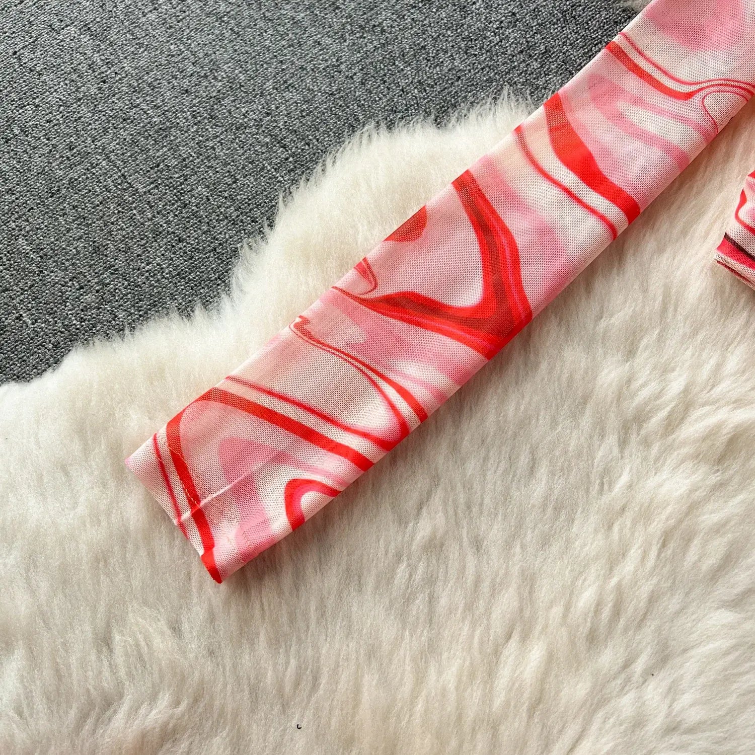 A delicate pink and red marbled silk scarf with flowing abstract patterns complements the two piece mesh skirt set marble print featuring an elastic closure type.