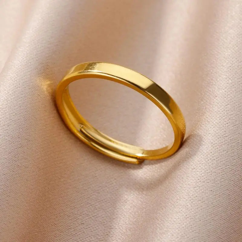 Un anillo de banda ajustable elegante de color dorado en acero inoxidable para mujeres, con acabado pulido suave y de estilo joyería de boda vintage.