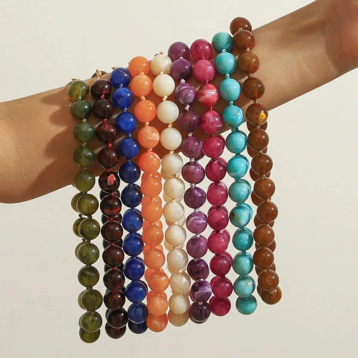 Ensemble de colliers ras du cou en résine à motif géométrique marbré, à perles, de forme ronde et multicolores, dans des tons vert, bleu, orange, rose et brun.