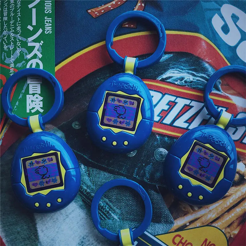 Blue Tamagotchi electronic virtual pet keychain with yellow accents and a small screen displaying pixelated characters, inspired by 90s handheld digital pet games.